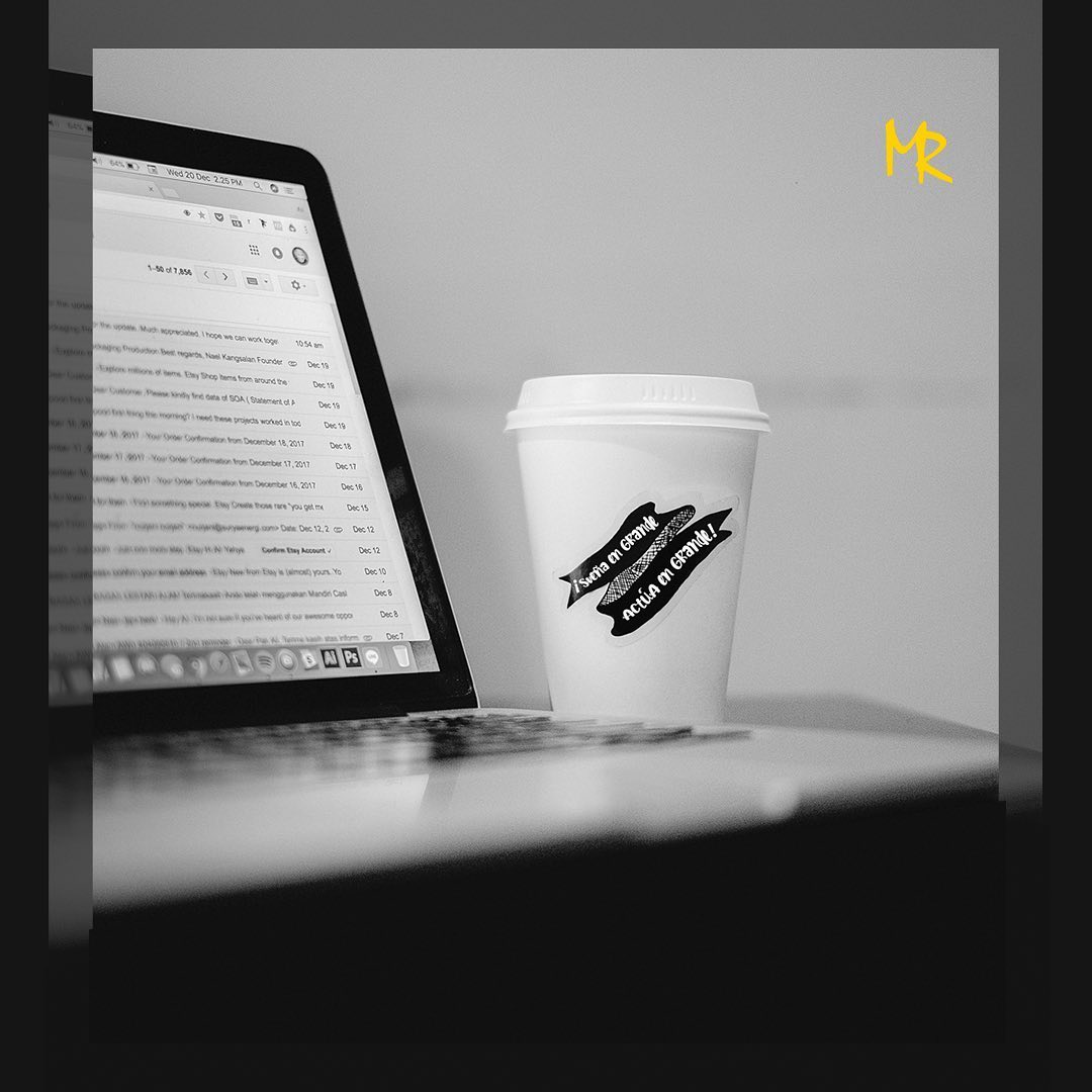 Un bote de café con una frase motivacional escrita en el junto a un ordenador portátil.